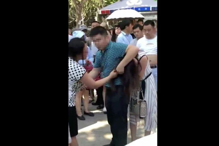 Dalam potongan video, nampak istri (kiri) menjambak rambut perempuan yang dituduh sebagai selingkuhan suaminya sementara si suami berusaha melerai mereka pada Rabu (18/7/2018).