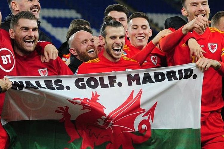 Bale dan rekan satu timnya membawa spanduk bertuliskan Wales. Golf. Madrid. seusai laga melawan Hongaria yang membuat Wales lolos ke putaran Piala Eropa 2020 pada Rabu (20/11/2019).