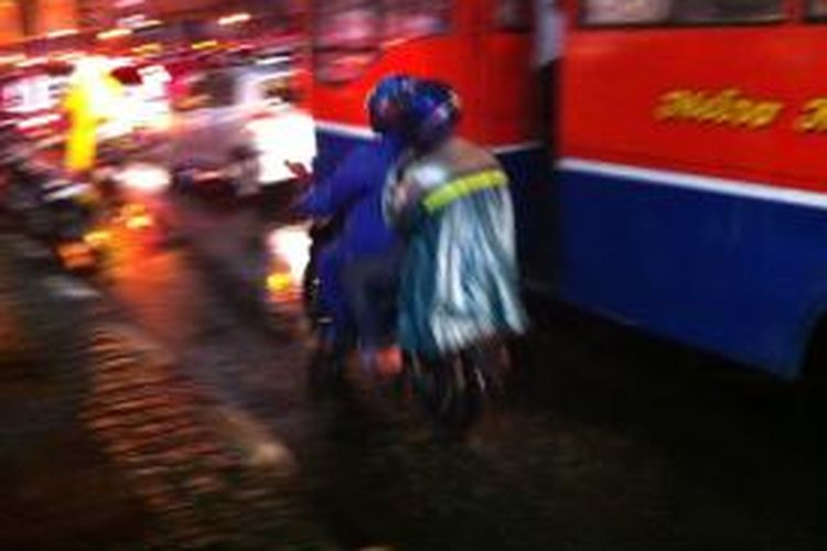 Pengendara sepeda motor yang menggunakan jas hujan ponco menutupi lampu rem dan sen.