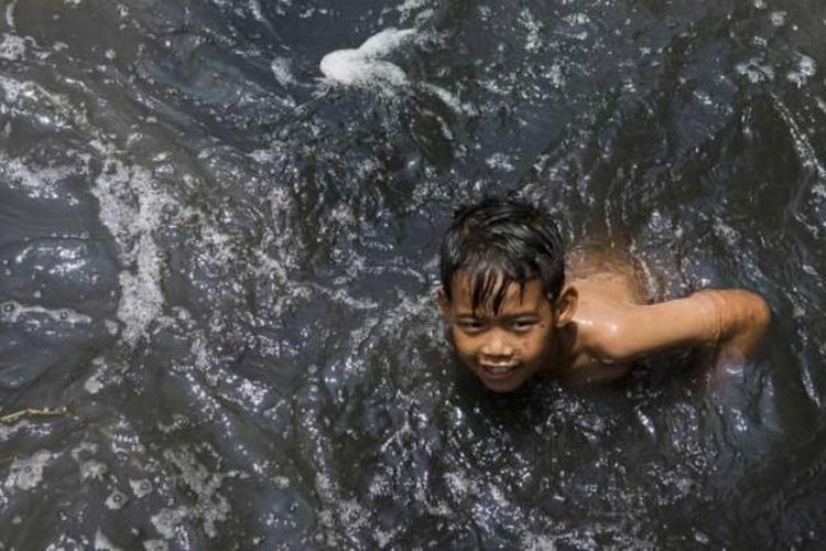 Seorang bocah mandi di Sungai Cikijing yang tercemar dengan limbah industri tekstil di Rancaekek, Bandung, yang airnya mengalir ke Sungai Citarum, 22 Maret 2015.