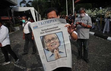 Pelayat membaca Harian Kompas yang menampilkan sosok  Pendiri Kompas Gramedia sekaligus Pemimpin Umum Harian Kompas Jakob Oetama  disela-sela  antre untuk memberikan penghormatan terakhir  di  Gedung Kompas Gramedia, Palmerah Selatan, Jakarta, Rabu (9/9/2020). Jakob Oetama tutup usia pada Kamis (10/9) pada usia ke 88  tahun di Rumah Sakit Mitra Keluarga Kelapa Gading, Jakarta. Selanjutnya, jenazah dikebumikan di  Taman Makam Pahlawan Kalibata, Jakarta, pada  Kamis (10/9).