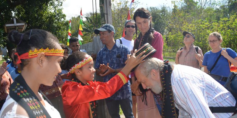 Seorang siswi SMPK Waemokel, Intan memakaikan topi songke kepada tamu Italia, di Kecamatan Kota Komba, Kabupaten Manggarai Timur, Flores, Nusa Tenggara Timur, Kamis (16/8/2018).