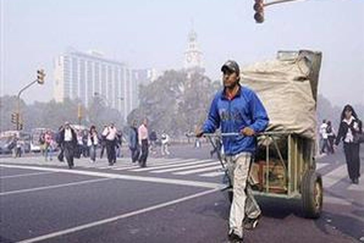 Seorang pemulung menarik gerobaknya di sebuah jalan Buenos Aires yang diliputi oleh asap tebal akibat kebakaran semak belukar pada pagi hari 18 April 2008. 