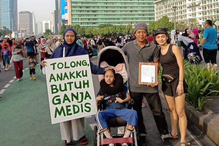 Santi Warastuti (43) bersama anaknya, Pika, dan suaminya, Sunarta, berjalan dari CFD ke Mahkamah Konstitusi (MK), Minggu (26/6/2022), perjuangkan agar ganja dilegalkan untuk pengobatan anaknya.