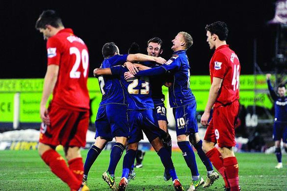 Pemain Oldham Athletic, Reece Wabara (tengah, 23), merayakan golnya ke gawang Liverpool bersama rekan satu tim pada laga putaran keempat Piala FA, Minggu (27/1) malam waktu Inggris, di Boundary Park, Oldham. Oldham Athletic menang 3-2 dan menyingkirkan Liverpool dari persaingan Piala FA.   