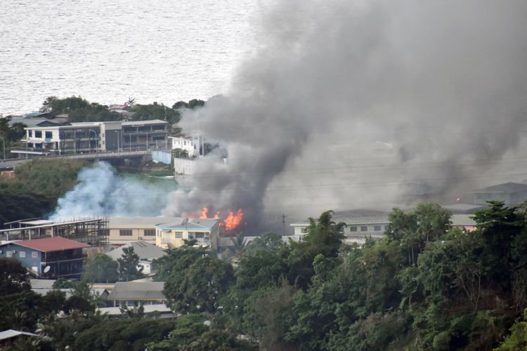 Asap terlihat dari gedung yang terbakar di Honiara, Kepulauan Solomon, pada Kamis 25 November 2021. Kepulauan Solomon dihantam demonstrasi hari kedua menyusul kemarahan rakyat karena janji pembangunan yang tak kunjung terealisasi, hingga kedekatan pemerintahnya dengan China dan memutuskan hubungan dengan Taiwan.