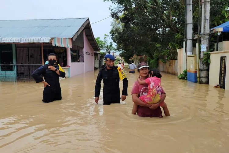 Seorang warga menggendong anaknya melintasi genangan air di Kota Tebing Tinggi pada Sabtu (28/11/2020). Satu pleton personil Brimob Batalyon B Pelopor Polda Sumut diturunkan untuk membantu proses evakuasi warga maupun barang.