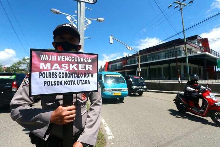 Petugas kepolisian memegang papan imbauan saat Operasi Yustisi penerapan protokol kesehatan di Jalan Jhon Aryo Katili di Kota Gorontalo, Gorontalo, Senin (14/9/2020). Operasi terpadu Polri dan Satpol PP tersebut dilakukan agar masyarakat patuh terhadap protokol kesehatan pencegahan COVID-19. ANTARA FOTO/Adiwinata Solihin/wsj.