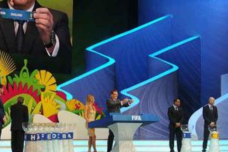 Sekretaris umum FIFA Jerome Valcke (tengah dan tampak di layar lebar) memperlihatkan kertas dengan tulisan nama Inggris saat undian Piala Dunia 2014 di Costa do Sauipe, Bahia, Brasil, Jumat (6/12/2013). Inggris tergabung di Grup D bersama Italia, Uruguay dan Kosta Rika.