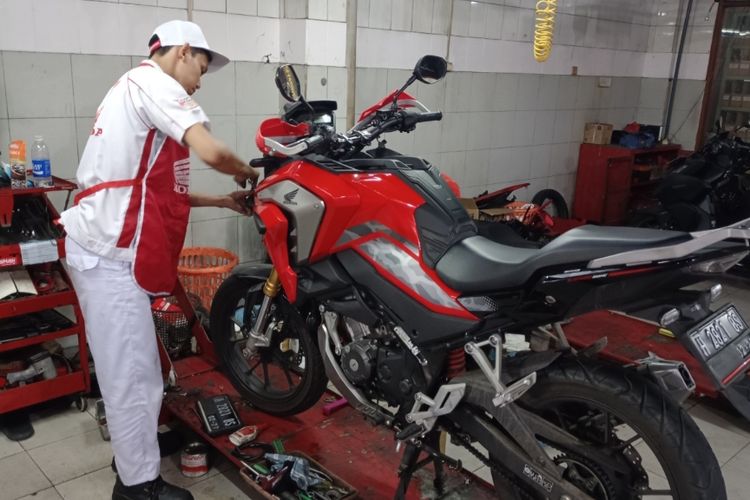 Mekanik bengkel resmi Astra Honda sedang memperbaiki kerusakan komponen sepeda motor. 