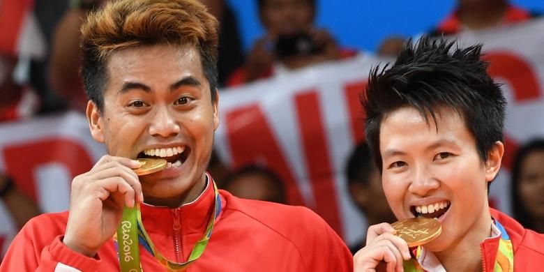 Pasangan ganda campuran Indonesia Tontowi Ahmad (kiri) dan Liliyana Natsir melakukan tradisi gigit medali emas. Mereka adalah peraih medali emas pertama untuk Indonesia pada Olimpiade 2016.