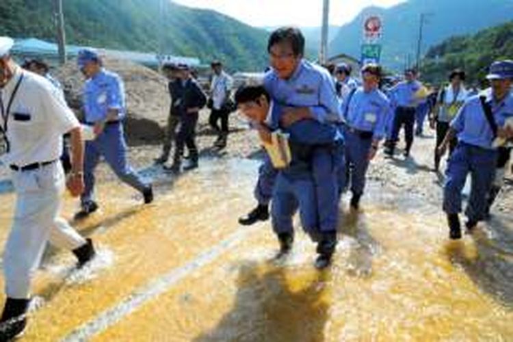 Seoran menteri senior Jepang, Shunsuke Mutai (60) tertangkap kamera sedang digendong bawahannya saat melintasi genangan air ketika meninjau sebuah daerah bencana.