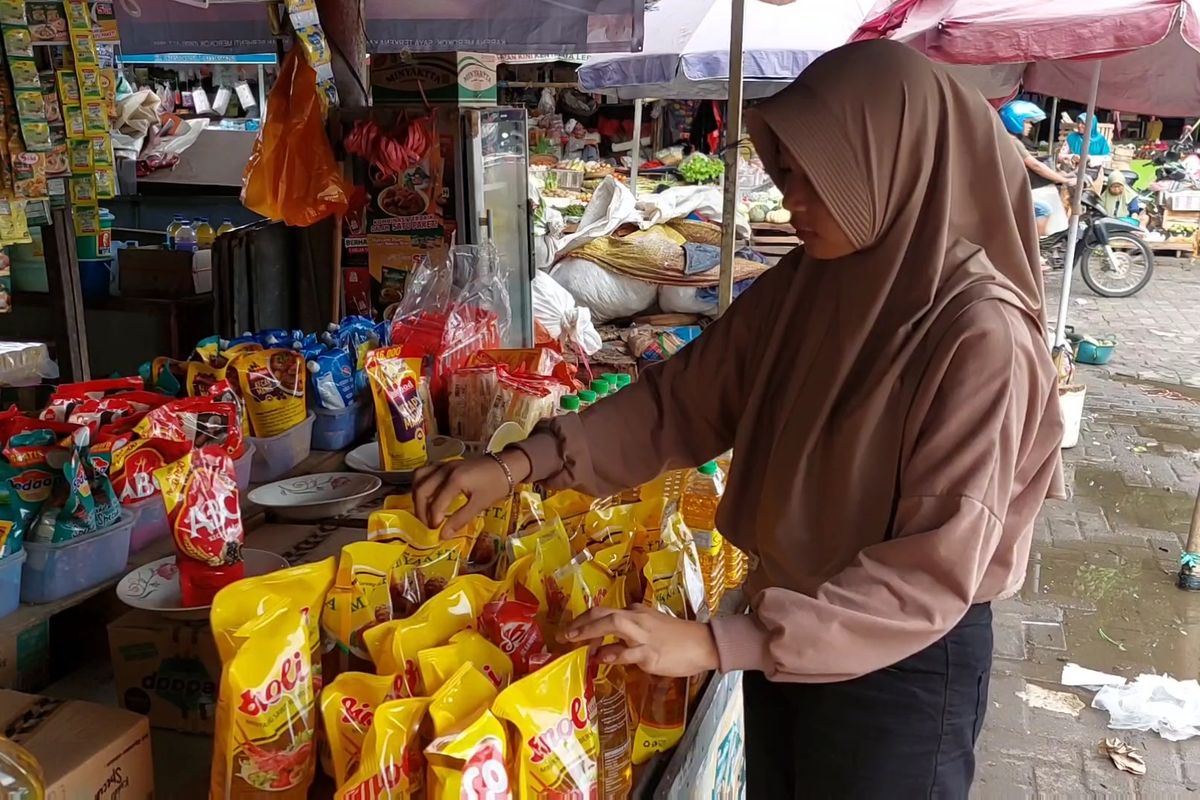 Seorang keryawan toko minyak di pasar tradisional Anom Sumenep menata barang jualannya.