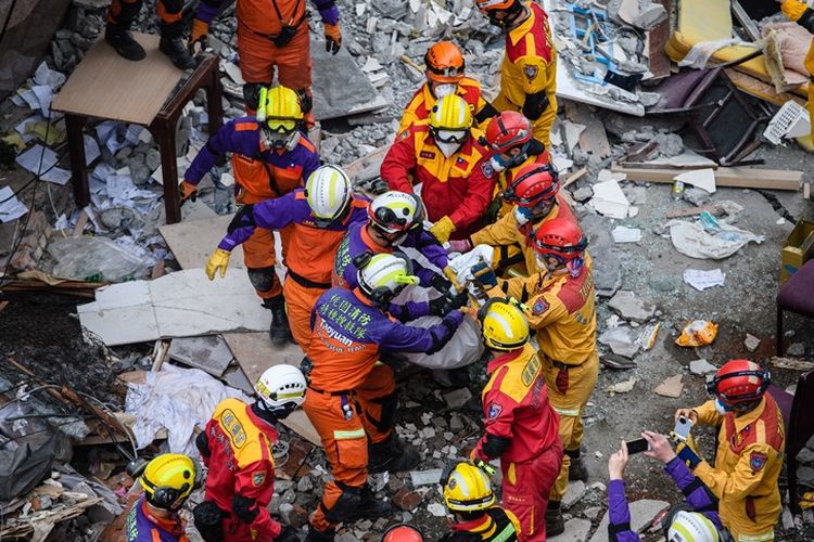 Petugas penyelamat bekerja sama memindahkan jenazah korban pertama yang ditemukan dalam gedung Yun Tsui, yang miring akibat gempa pada Selasa (9/2/2018) lalu. Hingga berakhirnya misi pencarian jumlah korban tewas total mencapai 17 orang.