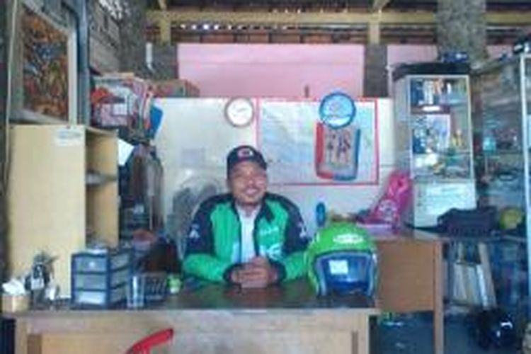 Budi Arifianto menjaga kios air mineral sambil menunggu order penumpang Gojek.