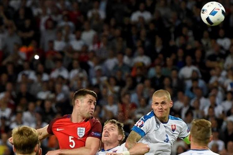 Bek Inggris, Gary Cahill, menyundul bola dalam kawalan ketat bek Slovakia, Tomas Hubocan (tengah), dan Martin Skrtel (tengah kanan) pada pertandingan Grup B Piala Eropa 2016 di Stadion Geoffroy-Guichard, Saint-Etienne, Senin (20/6/2016). 