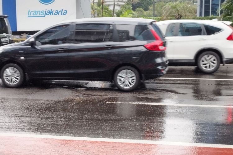 Mobil mengalami lonjakan kecil di Jalan Jenderal Sudirman depan Halte Tosari akibat kondisi jalan yang berlubang, Rabu (1/3/2023). (KOMPAS.com/XENA OLIVIA)