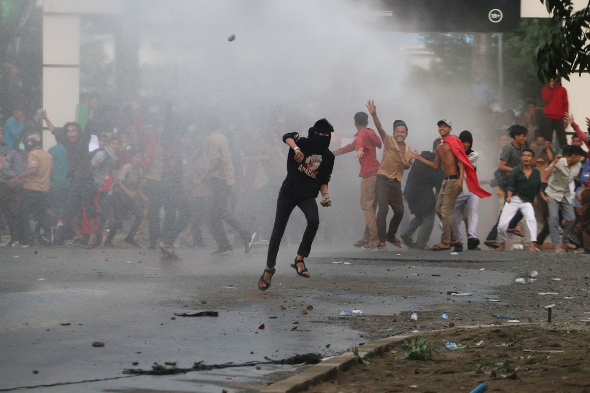 Massa melemparkan batu ke arah barisan polisi saat unjuk rasa menolak UU KPK hasil revisi dan RUU KUHP, di kawasan Titik Nol Kota Medan, Sumatera Utara, Jumat (27/9/2019). Unjuk rasa mahasiswa dan pelajar tersebut berakhir bentrok dengan petugas kepolisian, menyebabkan gedung DPRD Medan dan Sumut yang tak jauh dari lokasi itu rusak terkena lemparan. ANTARA FOTO/Irsan Mulyadi/ama.


