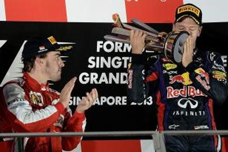 Pebalap Red Bull Racing asal Jerman, Sebastian Vettel (kanan) mencium trofi juara GP Singapura, sementara pebalap Ferrari asal Spanyol, Fernando Alonso yang finis kedua, melihat dan memberi tepuk tangan, di atas podium Sirkuit Marina Bay Street, Minggu (22/9/2013).