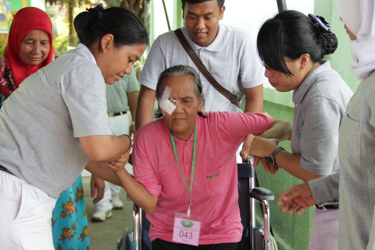 Para relawan Tzu Chi Sinar Mas membantu seorang pasien operasi katarak