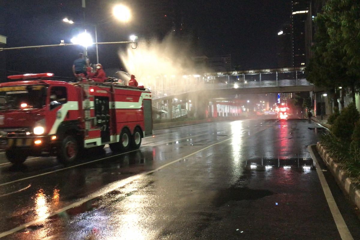 Anggota Suku Dinas Penanggulangan Kebakaran dan Penyelamatan DKI Jakarta menyemprotkan cairan disinfektan di sekitar Jalan Jenderal Sudirman-MH Thamrin, Jakarta pada Kamis (32/12/2020) malam.