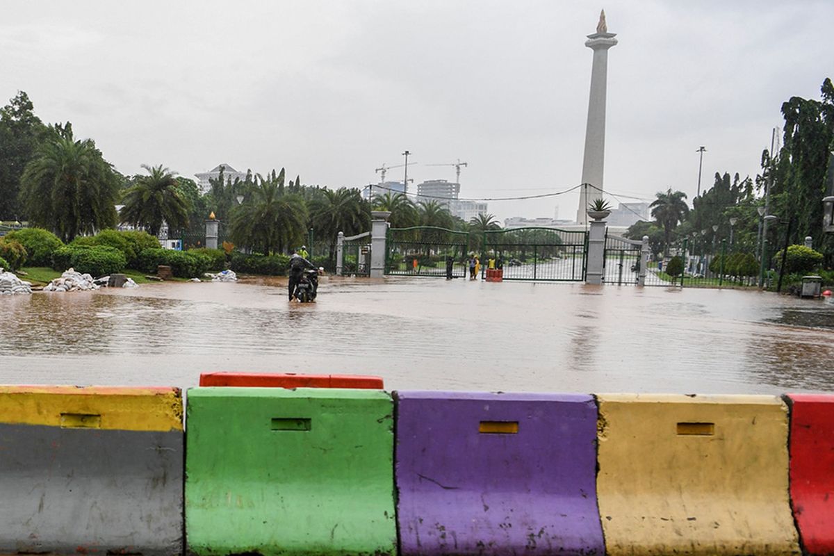 Warga mendorong motor melintasi banjir di kawasan Monas, Jalan Medan Merdeka Barat, Jakarta, Minggu (2/2/2020). Hujan deras yang mengguyur Jakarta pada Minggu (2/2) pagi menyebabkan beberapa ruas jalan di ibu kota tergenang banjir dengan ketinggian 10-50 centimeter.