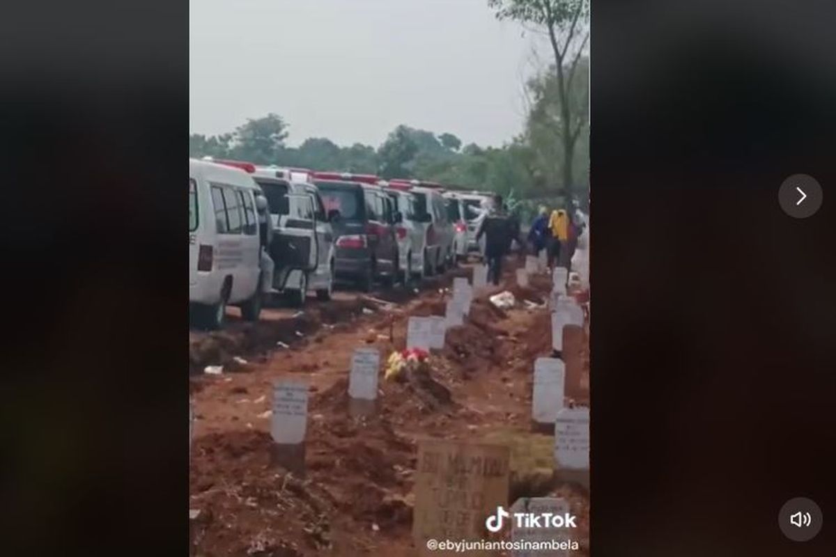 Suasana di TPU Pedurenan, Bekasi memperlihatkan deretan mobil jenazah yang mengantre untuk memakamkan jenazah. Semenjak dijadikan TPU Khusus jenazah pasien Covid-19, aktivitas di TPU Pedurenan tak pernah sepi dari pagi hingga malam sejak lonjakan kasus terjadi pasca libur lebaran.