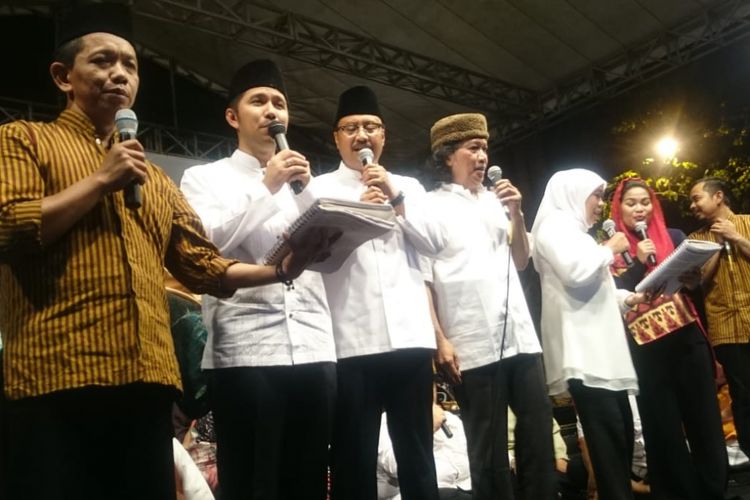 Dua pasangan cagub dan cawagub Jatim saling bergandengan di atas panggung sembari menyanyikan lagu Kemesraan, Selasa (26/6/2018). 