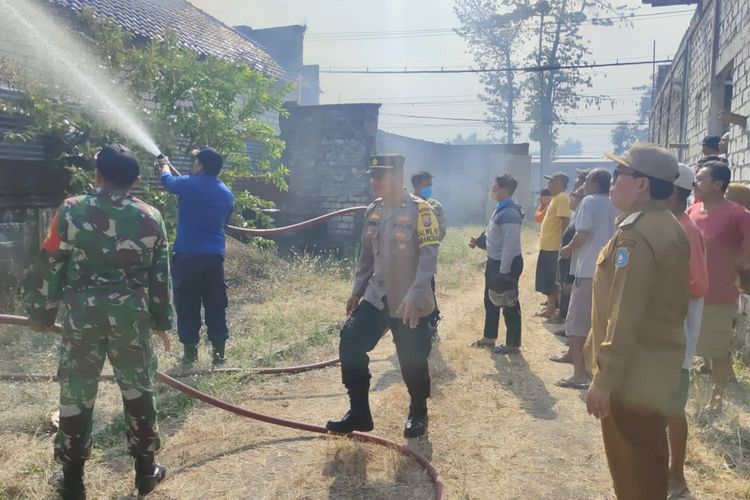 Petugas dibantu warga, pada saat memadamkan api yang membakar rumah dan kandang di Desa Pelang, Kecamatan Kembangbahu, Lamongan, Jawa Timur.