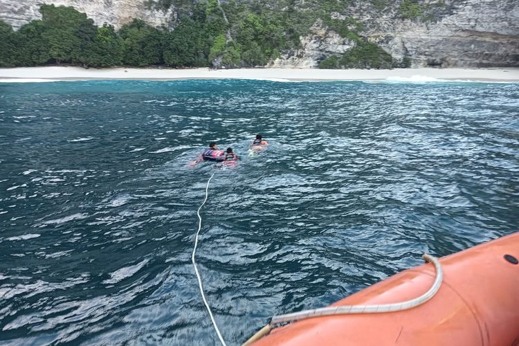 Tiga personel Tim SAR gabungan saat berenang menuju bibir pantai untuk mengevakuasi jenazah warga negara India, ST (29), yang tewas terseret ombak di pantai Kelingking, Nusa Penida, Klungkung, Bali, pada Jumat (9/6/2023). /Dok. Humas Basarnas Bali