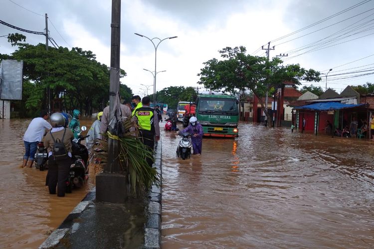 Pengendara yang melintas menuntun motornya melewati banjir di kawasan Mangkang, Sabtu (6/2/2021).