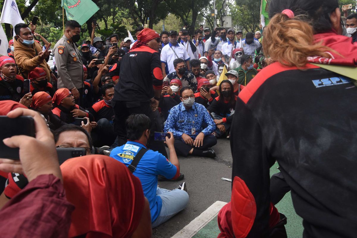 Gubernur DKI Jakarta Anies Baswedan (tengah) duduk bersama buruh yang berunjuk rasa menolak besaran kenaikan Upah Minimum Provinsi (UMP) di depan Balai Kota DKI Jakarta, Senin (29/22/2021). Anies Baswedan pada kesempatan tersebut mengatakan formula penetapan UMP yang tertuang dalam Peraturan Pemerintah (PP) Nomor 36 Tahun 2021 tentang Pengupahan tidak cocok diterapkan di Jakarta.