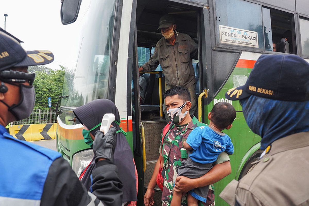 Petugas gabungan Polri dan Dishub melakukan pemantauan suhu tubuh penumpang bus yang turun di pintu tol Bekasi Timur, Bekasi, Jawa Barat, Rabu (15/4/2020). Pemberlakuan PSBB di Jawa Barat yang berlaku hari ini masih ada pengendara yang masih belum tertib dalam menjalankan arahan pengendalian COVID-19.