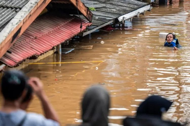 Seorang warga melintasi banjir di Pancoran, Jakarta Selatan pada 4 Maret 2025.