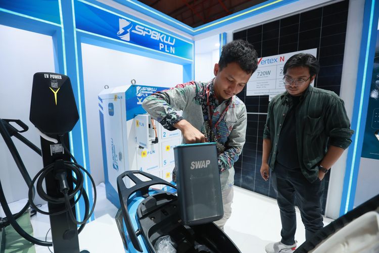 Salah satu pengunjung IIMS 2025 antusias melihat simulasi penukaran baterai motor listrik di booth PLN.
