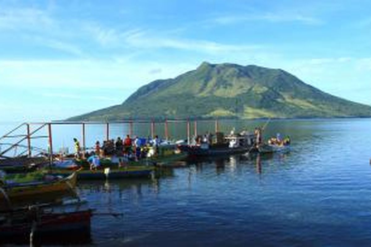 Nelayan sedang membongkar hasil aktifitas mereka di Tagulandang dengan latar belakang Gunung Api Ruang, di Kabupaten Kepulauan Sitaro, Sulawesi Utara.