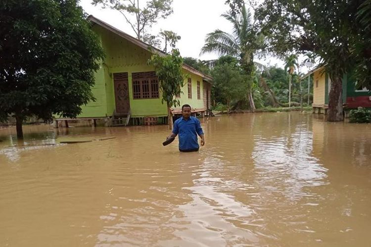 Warga melintasi banjir di Kecamatan Banda Alam, Kabupaten Aceh Timur, Minggu (9/10/2022). 
