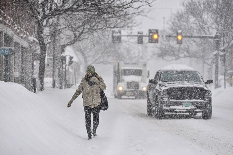 Saat salju menumpuk, seorang pejalan kaki, Gina Hanson, dari Brattleboro, Vt., Berjalan di Jalan Utama Brattleboro selama badai salju pada Kamis, 17 Desember 2020.