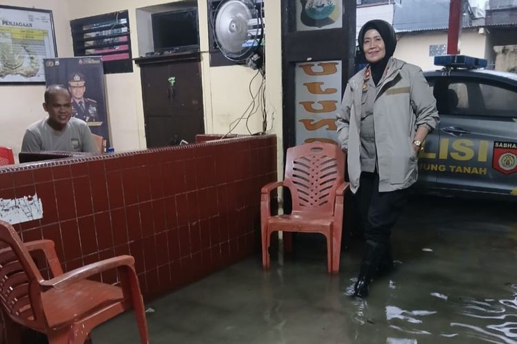 Kapolsek Ujung Tanah Kompol Andriani Lilikay (berdiri) bersama seorang anggotanya saat berada di lobi kantornya yang tergenang air akibat hujan yang melanda Kota Makassar, Sulsel, Jumat (12/1/2024)