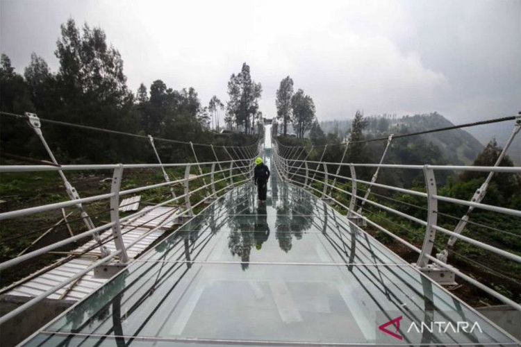 Pekerja berjalan di atas jembatan gantung kaca di Seruni Point Kawasan Strategis Pariwisata Nasional (KSPN) Bromo-Tengger-Semeru, Probolinggo, Jawa Timur, Selasa (29/11/2022)