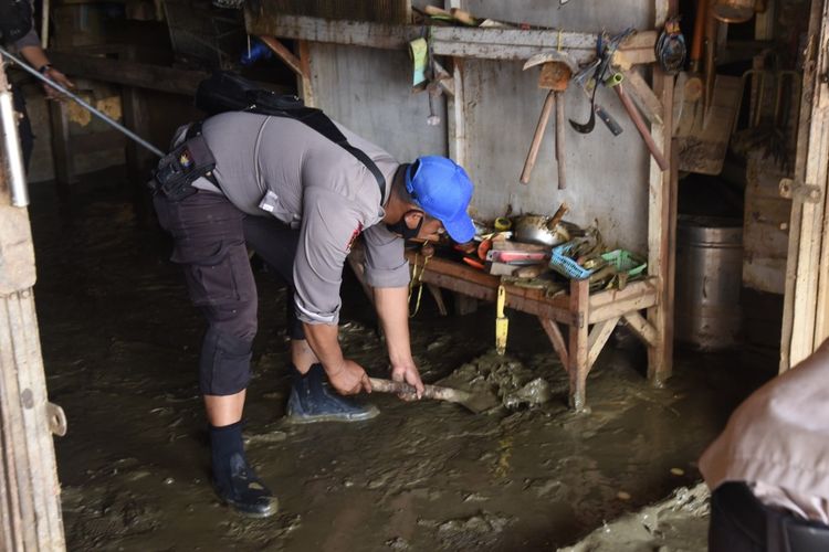 Salah satu personel Polri yang tengah membantu membersihkan rumah warga yang terdampak bencana banjr, Kota Jayapura, Papua, Senin (10/1/2022)