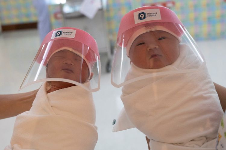 Perawat menggendong dua bayi baru lahir yang mengenakan kaca pelindung selama wabah virus corona (Covid-19) di Rumah Sakit Praram 9 di Bangkok, Thailand, pada 9 April 2020.