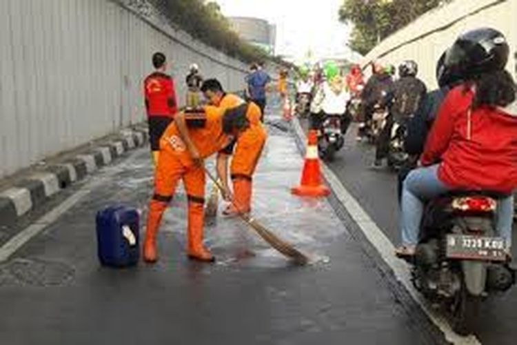 Petugas membersihkan tumpahan oli di jalan