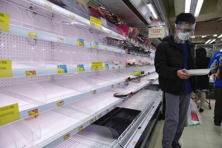 Seorang pria yang mengenakan topeng pelindung berdiri di samping rak-rak kosong daging saat penduduk khawatir tentang kekurangan makanan segar, di sebuah supermarket di Hong Kong Senin, 28 Februari 2022. 