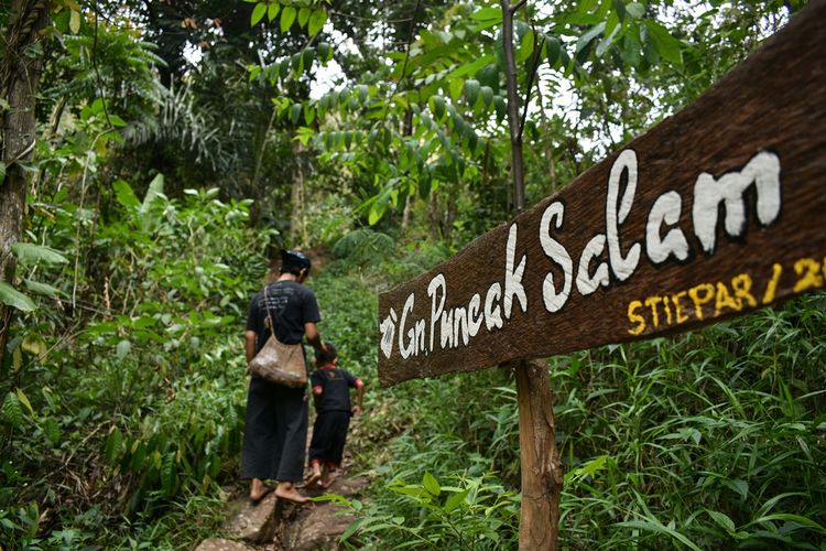 Kang Entri (35) dan anak lelakinya memasuki hutan tutupan di Gunung Puncak Salam di wilayah Kampung Adat Cireundeu, Kelurahan Lewigajah, Kecamatan Cimahi Selatan, Kota Cimahi. Tampak petunjuk memasuki jalur gunung.