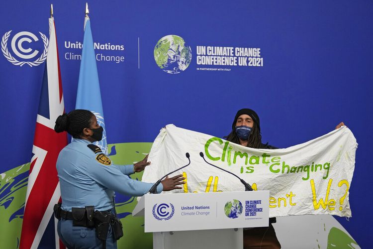 Seorang anggota keamanan menahan seorang demonstran pada COP26 di Glasgow, Skotlandia, Sabtu (13/11/2021). Hampir 200 negara telah menerima kompromi iklim yang bertujuan untuk menjaga kenaikan suhu bumi, tetapi berisi perubahan pada menit terakhir tentang batu bara.