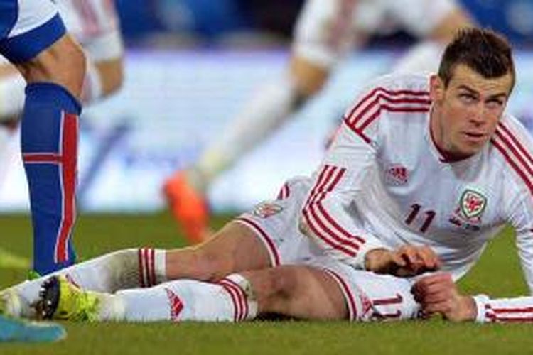 Pemain Wales, Gareth Bale, terjatuh karena ditekel pemain Islandia dalam laga uji coba di Cardiff City Stadium, Cardiff, Wales selatan, Rabu (5/3/2014).