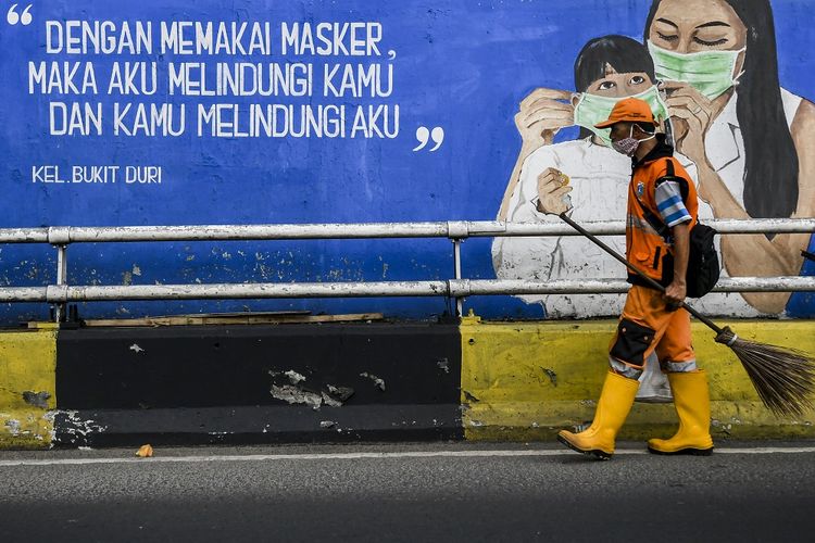 Petugas kebersihan melintas di depan mural tentang pandemi COVID-19 di Kawasan Tebet, Jakarta, Selasa (15/9/2021). Gubernur DKI Jakarta Anies Baswedan memperpanjang masa pemberlakuan pembatasan kegiatan masyarakat (PPKM) berbasis mikro selama dua pekan atau hingga 28 Juni 2021, hal tersebut dilakukan karena penyebaran COVID-19 di Jakarta dalam kondisi yang memerlukan perhatian ekstra. ANTARA FOTO/Galih Pradipta/foc.