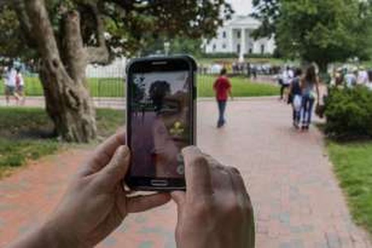 Seorang wanita memegang ponsel saat dia memainkan game Pokemon Go di Taman Lafayette di depan Gedung Putih, Washington DC, Selasa (12/7/2016).