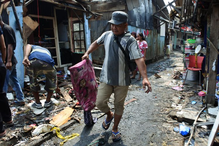 Seorang pria membawa bantal basah akibat terkena air saat proses pemadaman kebakaran permukiman di RT 10 RW 01, Kelurahan Semenan, Kecamatan Kalideres, Jakarta Barat, Kamis (29/8/2019).